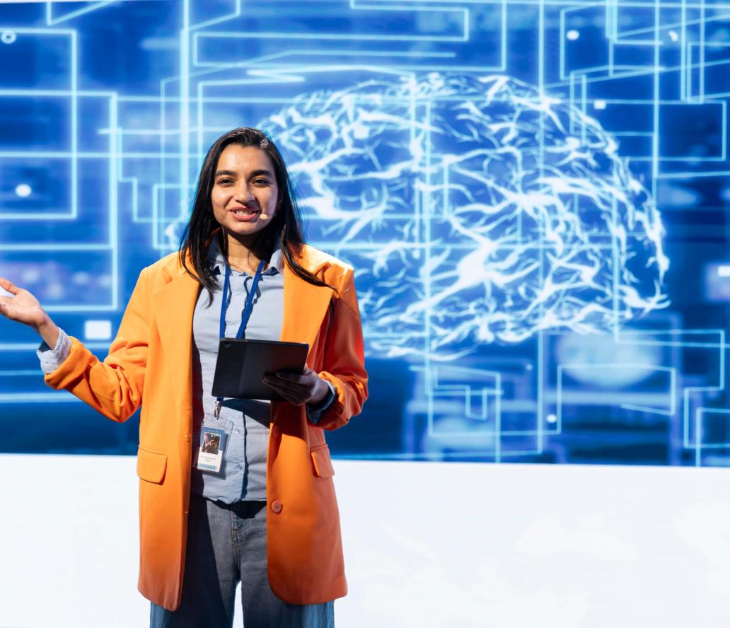 Cheerful engineer holding presentation at AI tech summit using tablet Cheerful engineer holding presentation at AI tech summit event gathering professionals using tablet. Jolly speaker using device to present how can AI be leveraged to accelerate innovation